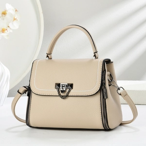 Elegant beige crossbody bag with contrast stitching and metal chain detail in home setting