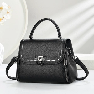 Close-up of black lychee grain leather bag with silver rivets and metal chain detail
