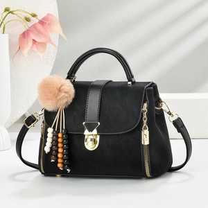 Classic black crossbody bag with gold hardware and plush pompom tassel charm
