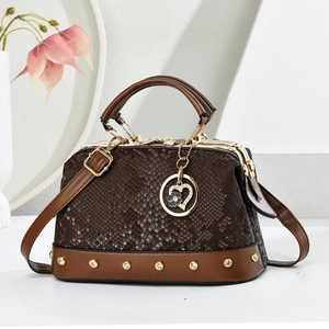 Brown snake-embossed satchel bag with gold rivets and heart pendant on white background