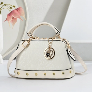 Detail of white snakeskin texture handbag with golden rivets and a heart pendant charm