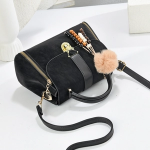Detail of black suede Boston bag with gold hardware and bohemian beaded bag charms