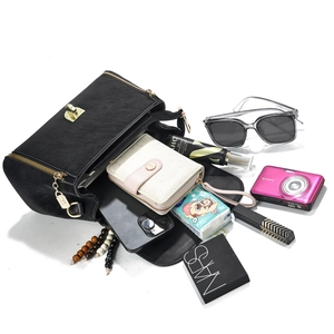 Detail showing high-capacity black leather handbag interior with gold metal lock hardware