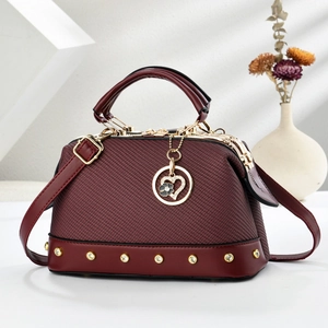 Elegant wine red handbag with herringbone texture and gold heart charm on a white background