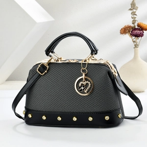 Detail of dark grey textured tote bag featuring gold rivets and heart flower charm