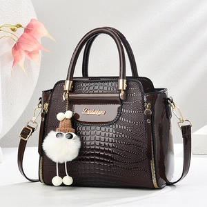 Détails du sac à main en cuir de crocodile chocolat avec charm en peluche et métal doré