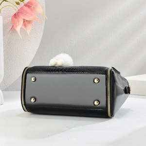 Détail du sac à main noir croco avec clous dorés et breloque pompon blanc soyeux