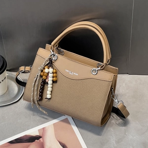Khaki Handtasche aus PU-Leder mit Webstruktur und Perlenanhänger auf Steintisch