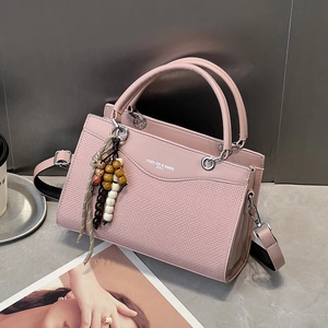 Rosa Handtasche mit Webstruktur, Perlenanhänger und breitem Gurt auf Marmortisch