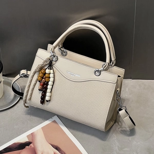 Detail der beigen Henkeltasche mit gewebtem Leder und buntem Holzperlen-Anhänger für Damen