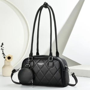 Detail of black quilted tote bag with silver hardware and small round coin purse charm