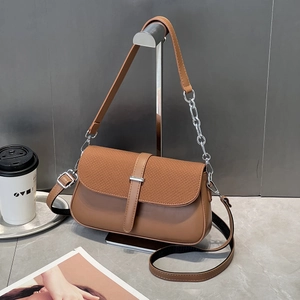 Macro detail of brown woven texture and smooth leather finish on a chic crossbody bag