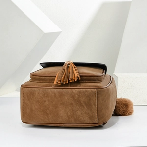 Detailed view of brown faux leather backpack with black flap and tassel decoration