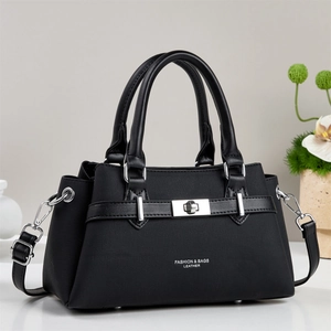 Chic black handbag with silver metal twist lock and detachable shoulder strap on white desk