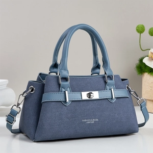 Navy blue leather handbag with light blue handle and silver lock in a minimalist scene