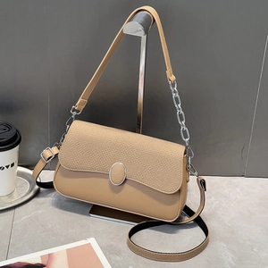 Detail of tan crossbody bag featuring woven texture flap and silver metal buckle