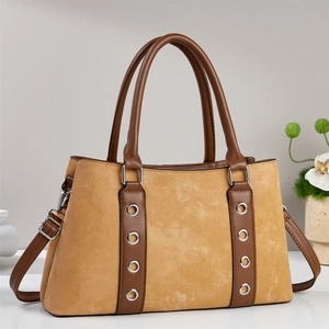 Détail du sac à main en daim gingembre avec œillets métalliques et bandoulière en cuir brun