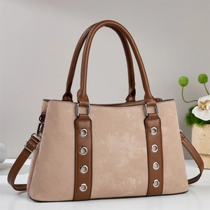 Vue détaillée d'un sac à main rétro beige et marron avec des détails d'œillets en métal