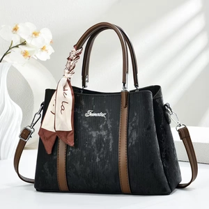 Dettaglio borsa nera con finiture in pelle marrone e sciarpa di seta decorativa