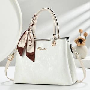 Minimalist white textured handbag with gold hardware and silk scarf on plain background