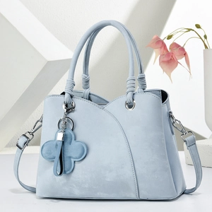 Sac à main élégant en similicuir bleu clair avec pendentif trèfle sur fond épuré