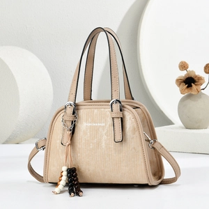 Detail of beige handbag featuring vertical striped texture and beaded tassel decoration