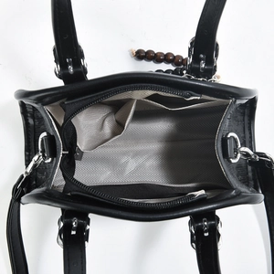 Internal view of black handbag with grey herringbone lining and functional compartments