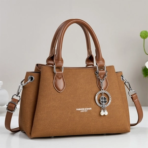 Brown leather tote bag with woven texture, dual handles and clover charm pendant