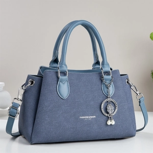 Navy blue textured leather handbag with light blue handles and a clover charm