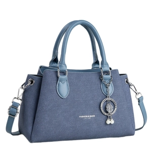 Blue denim textured trapezoid handbag with dual handles and clover pearl charm detail