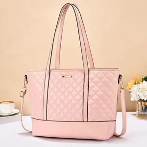 Pink quilted tote bag with diamond pattern and detachable shoulder strap on desk