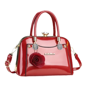Elegant red patent leather shell handbag with gold hardware and rose floral pendant charm