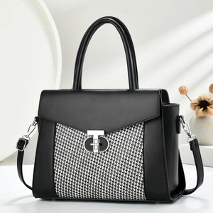 Detail of a chic trapezoid handbag with black and white woven texture and silver lock