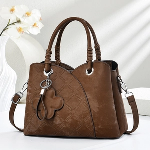 Detailed view of brown handbag with rhombus pattern, flower charm and knotted handle