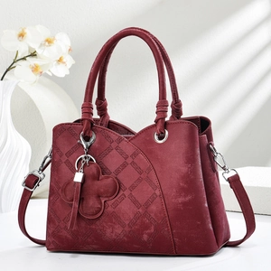 Detail of burgundy quilted leather handbag with silver hardware and knotted handle