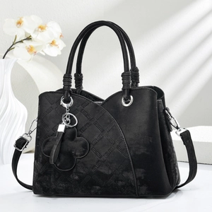 Detail of black quilted shoulder bag featuring silver hardware and a floral leather pendant