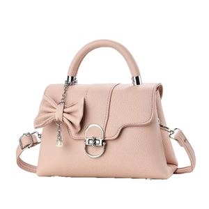 Pink litchi grain leather handbag with decorative bow and pearl pendant on white background