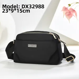 Detail view of the black nylon crossbody bag with 23x9x15cm dimensions and gold logo