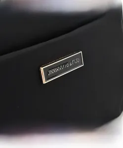 Detailed macro view of the gold-tone logo plaque and durable black nylon fabric texture