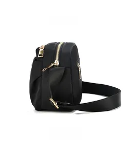 Detail of black nylon crossbody bag with gold zippers and side pleated design