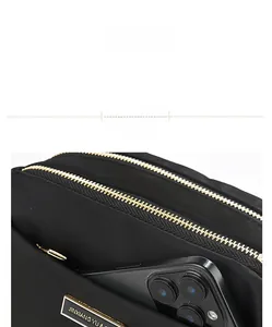 Detailed view of the black nylon shoulder bag with gold zippers and phone storage capacity