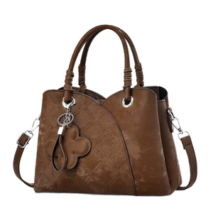 Dark brown faux leather tote bag with diamond quilting and floral charm on white background