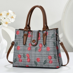 Close-up of grey plaid texture canvas tote bag featuring red cherry prints and brown strap