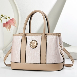 Detail of striped tote bag showing golden G metal logo and pink textured panel