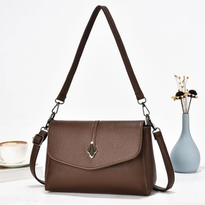 Détail du sac à main vintage en cuir marron avec boucle feuille sur un fond blanc épuré
