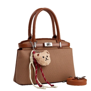 Brown woven crossbody bag with leather handles and cute plush bear charm decoration