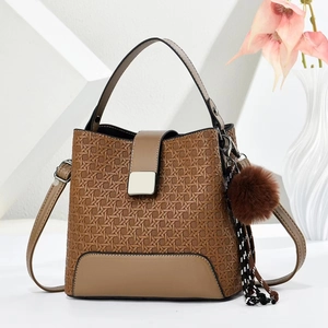 Détail du sac à main marron tissé avec fermoir doré et accessoire boule en peluche