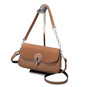 Brown leather crossbody box bag with woven flap and silver horseshoe clasp on white backdrop