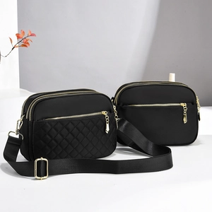 Detail of two black nylon crossbody bags with multiple zippers and wide straps