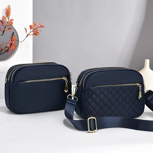Detail of dark blue nylon crossbody bags with diamond quilting and gold-tone zippers